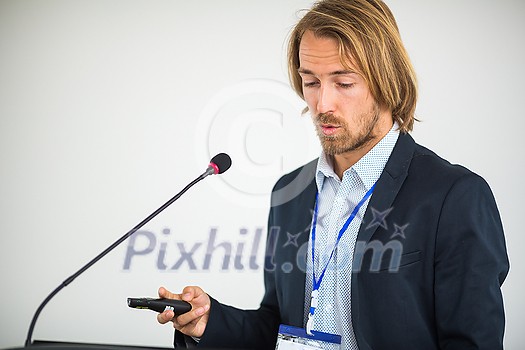 Handsome young man giving a speech at a conference Handsome young man giving a speech at a conference