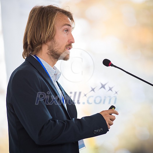 Handsome young man giving a speech at a conference Handsome young man giving a speech at a conference