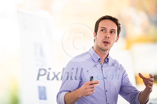 Handsome young man giving a speech at a conference Handsome young man giving a speech at a conference