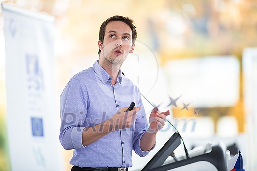 Handsome young man giving a speech at a conference Handsome young man giving a speech at a conference
