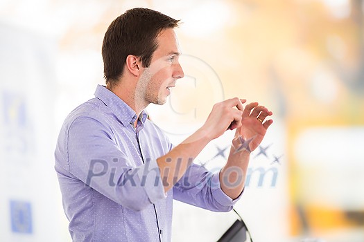 Handsome young man giving a speech at a conference Handsome young man giving a speech at a conference