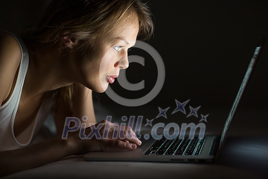 Pretty, young woman using her laptop computer in bed (color toned image; shallow DOF) Pretty, young woman using her laptop computer in bed (color toned image; shallow DOF)