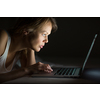 Pretty, young woman using her laptop computer in bed (color toned image; shallow DOF)