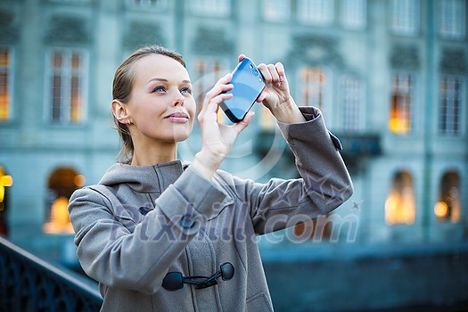 Elegant, young woman taking a photo with her cell phone camera while traveling (shallow DOF; color toned image) Elegant, young woman taking a photo with her cell phone camera while traveling (shallow DOF; color toned image)