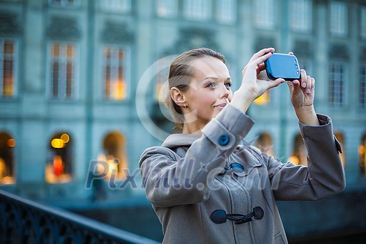 Elegant, young woman taking a photo with her cell phone camera while traveling (shallow DOF; color toned image) Elegant, young woman taking a photo with her cell phone camera while traveling (shallow DOF; color toned image)