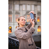 Elegant, young woman taking a photo with her cell phone camera while traveling (shallow DOF; color toned image)
