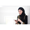 young modern muslim business woman using smartphone wearing traditional hijab clothes at home