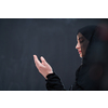 portrait of beautiful muslim woman in fashionable dress with hijab making traditional prayer to God keeps hands in praying gesture isolated on black chalkboard background representing modern islam fashion and ramadan kareem concept