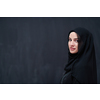 portrait of beautiful muslim woman in fashionable dress with hijab in front of black chalkboard representing modern islam fashion and ramadan kareem concept