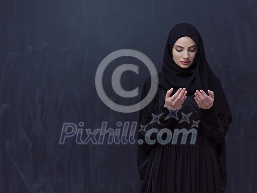 portrait of beautiful muslim woman in fashionable dress with hijab making traditional prayer to God, keeps hands in praying gesture isolated on black chalkboard background representing modern islam fashion and ramadan kareem concept portrait of beautiful muslim woman in fashionable dress with hijab making traditional prayer to God, keeps hands in praying gesture isolated on black chalkboard background representing modern islam fashion and ramadan kareem concept
