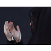 portrait of beautiful muslim woman in fashionable dress with hijab making traditional prayer to God, keeps hands in praying gesture isolated on black chalkboard background representing modern islam fashion and ramadan kareem concept