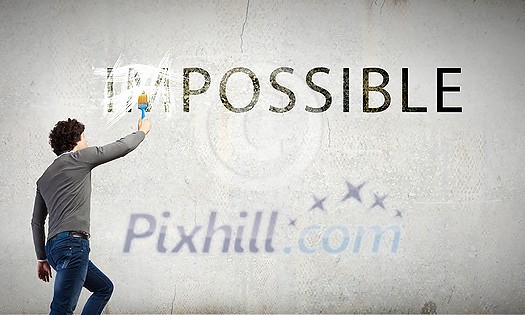 Man changing word impossible in to possible by erasing part of word with paint brush Man changing word impossible in to possible by erasing part of word with paint brush