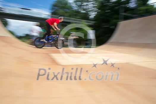 Bmx rider jumping over on a U ramp in a skatepark (motion blurred image) Bmx rider jumping over on a U ramp in a skatepark (motion blurred image)