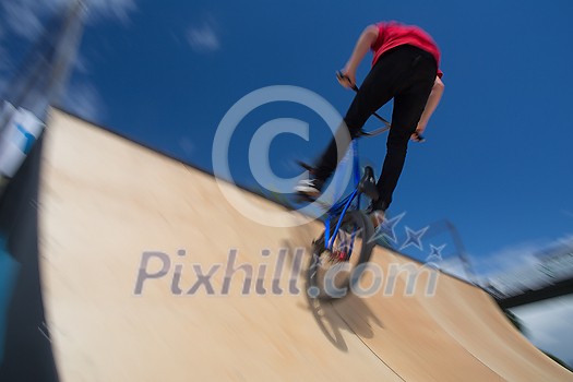 Bmx rider jumping over on a U ramp in a skatepark (motion blurred image) Bmx rider jumping over on a U ramp in a skatepark (motion blurred image)