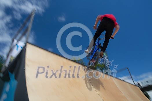 Bmx rider jumping over on a U ramp in a skatepark (motion blurred image) Bmx rider jumping over on a U ramp in a skatepark (motion blurred image)