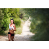 Beautiful young female runner on a forest path, on a lovely summer day