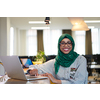 african muslim business woman wearing a green hijab while working on laptop computer in relaxation area at modern open plan startup office. Diversity, multiracial concept