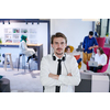 portrait of successful businessman entrepreneur with headphones around his neck and colleagues in the background at busy startup office