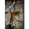A rock climber climbing on a boulder rock outdoors. Group of friends involved in sports outside.