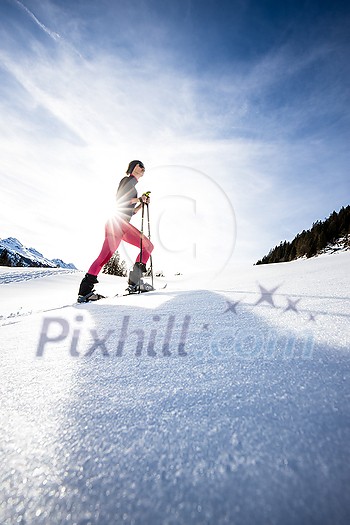Young woman snowshoeing in high mountains, enjoying a lovely day Young woman snowshoeing in high mountains, enjoying a lovely day