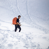 Winter sports - young man walking with snowshoes/touring skis in high mountains covered with lots of snow (selective focus on the mountain in the background)