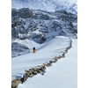 Winter sports - young man walking with snowshoes uphill in high mountains covered with lots of snow