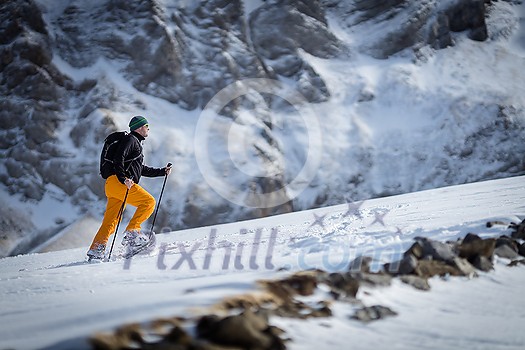 Winter sports - young man walking with snowshoes uphill in high mountains covered with lots of snow Winter sports - young man walking with snowshoes uphill in high mountains covered with lots of snow