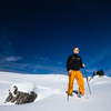 Winter sports - young man walking with snowshoes uphill in high mountains covered with lots of snow (selective focus on the mountain in the background)