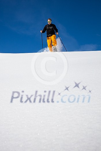 Winter sports - young man running with snowshoes downhill in high mountains covered with lots of snow Winter sports - young man running with snowshoes downhill in high mountains covered with lots of snow