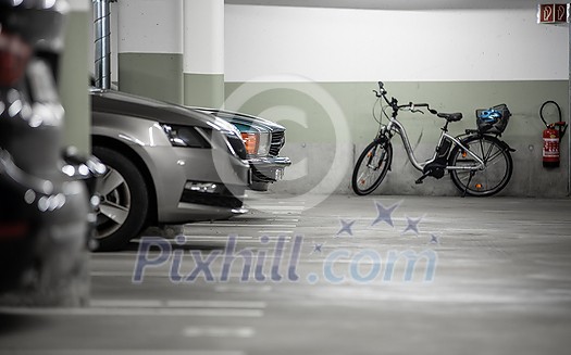 Underground parking. Cars parked in a garage with no people. Many cars in parking garage interior. Underground parking with cars (color toned image) Underground parking. Cars parked in a garage with no people. Many cars in parking garage interior. Underground parking with cars (color toned image)