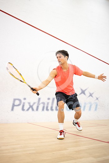 Squash player in action on a squash court (motion blurred image; color toned image) Squash player in action on a squash court (motion blurred image; color toned image)