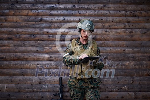 woman soldier using tablet computer against old wooden wall in camp woman soldier using tablet computer against old wooden wall in camp