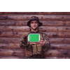 Soldier using tablet computer against old wooden wall in military camp to stay in contact with friends and family