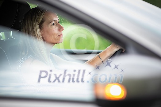 Pretty midle aged woman at the steering wheel of her car commuting to work Pretty midle aged woman at the steering wheel of her car commuting to work