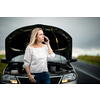 Pretty middle aged woman having car troubles - broken down car on the side of the road, calling the insurance company for assistance
