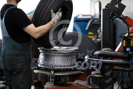 Car mechanic changind tires of a car in a repair shop/car garage (shallow DOF/color toned image) Car mechanic changind tires of a car in a repair shop/car garage (shallow DOF/color toned image)