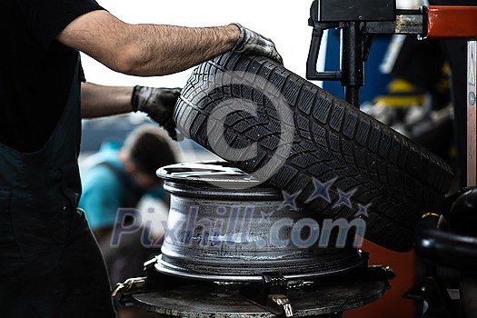Car mechanic changind tires of a car in a repair shop/car garage (shallow DOF/color toned image) Car mechanic changind tires of a car in a repair shop/car garage (shallow DOF/color toned image)
