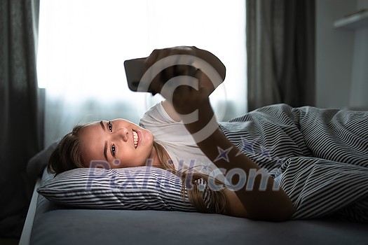 Pretty, young woman sleeping in her bed with her cell phone close to her. Smartphone in Bed Mobile/smartphone Addiction Concept. Pretty, young woman sleeping in her bed with her cell phone close to her. Smartphone in Bed Mobile/smartphone Addiction Concept.