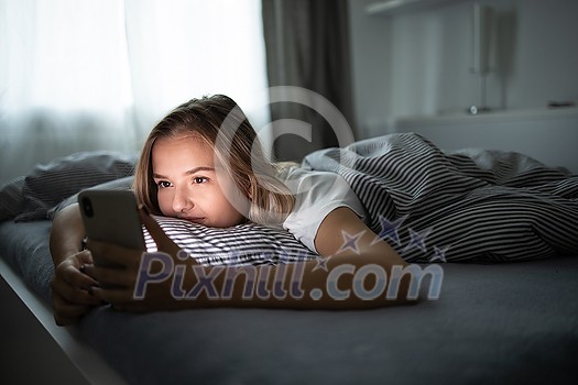 Pretty, young woman sleeping in her bed with her cell phone close to her. Smartphone in Bed Mobile/smartphone Addiction Concept. Pretty, young woman sleeping in her bed with her cell phone close to her. Smartphone in Bed Mobile/smartphone Addiction Concept.
