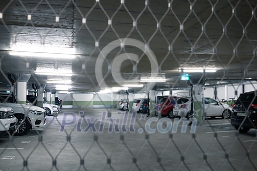 Underground parking. Cars parked in a garage with no people. Many cars in parking garage interior. Underground parking with cars (color toned image) Underground parking. Cars parked in a garage with no people. Many cars in parking garage interior. Underground parking with cars (color toned image)
