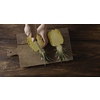 Woman's hands are cutiing the halves of fresh yellow natural tropical pineapple in a quater. Four parts of fruit on a cutting board on a wooden table. Top view. Motion, 4K UHD video, 3840, 2160p.