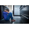 Depressed young woman, sitting on the kitchen floor, feeling down