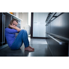 Depressed young woman, sitting on the kitchen floor, feeling down