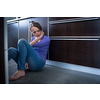 Depressed young woman, sitting on the kitchen floor, feeling down
