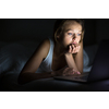Pretty, young woman using her laptop computer in bed (color toned image; shallow DOF)