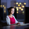 Pretty, young female college student using a desktop computer/pc in a college library (shallow DOF; color toned image)