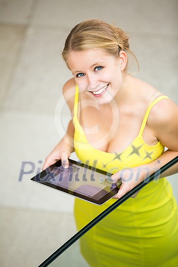 Cute, femle student using a tablet computer in a library/on uni campus Cute, femle student using a tablet computer in a library/on uni campus