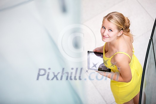 Pretty, young woman using a tablet computer in corporate context Pretty, young woman using a tablet computer in corporate context