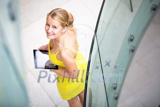 Pretty, young woman using a tablet computer in corporate context Pretty, young woman using a tablet computer in corporate context