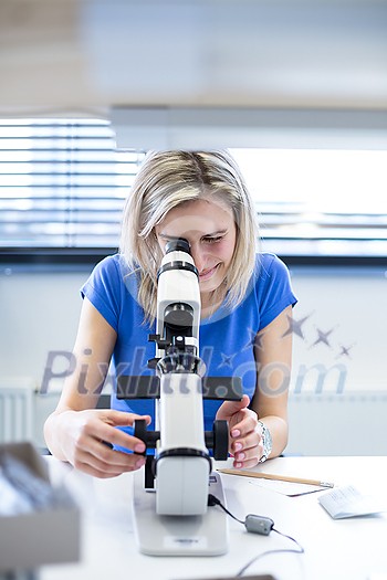 Pretty, female optometrist measuring newly made glasses - veryfing it is spot on Pretty, female optometrist measuring newly made glasses - veryfing it is spot on